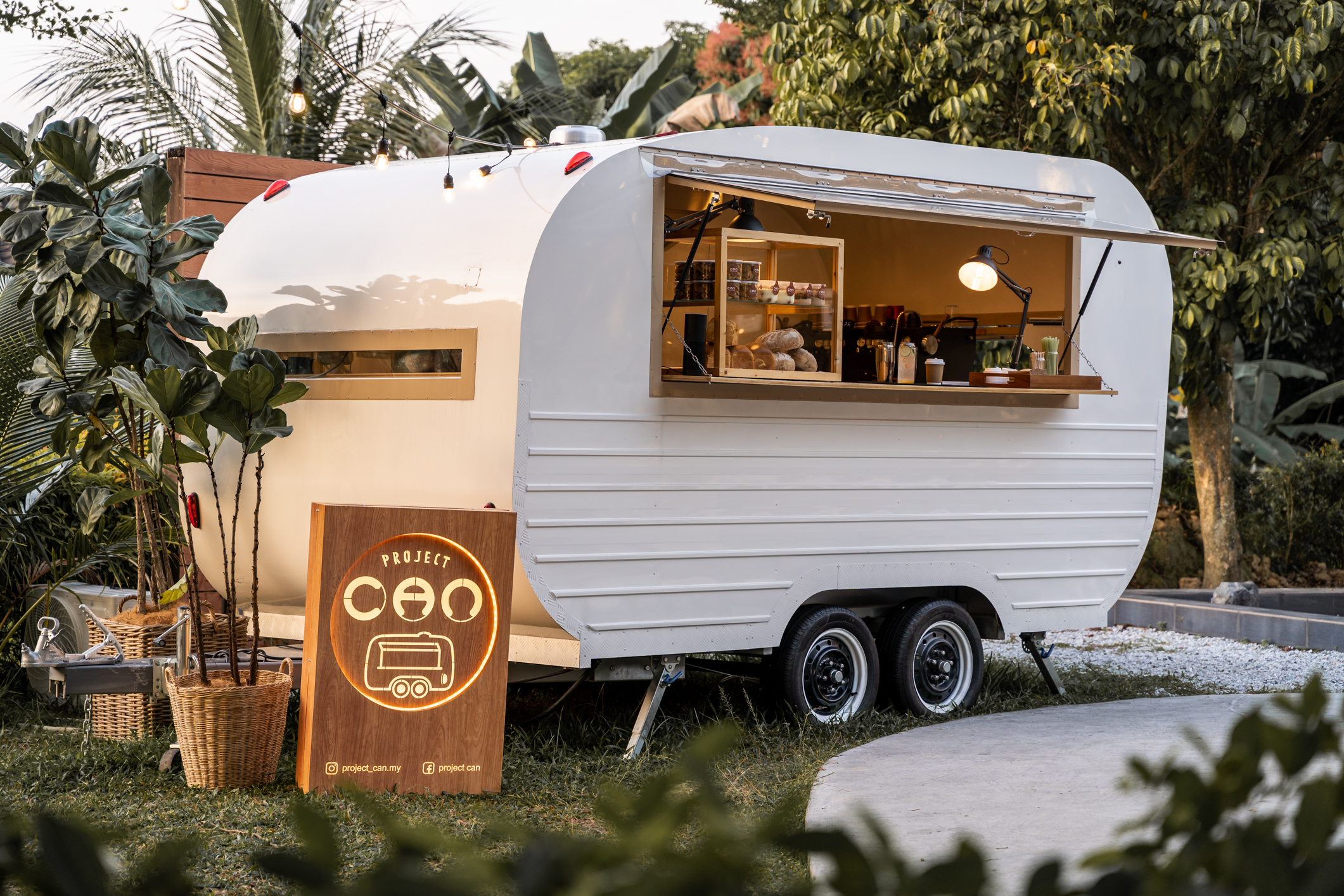 Project CAN’s caravan café surrounded by greenery at golden hour